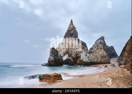 Riesenfelsen am Ende des Strandes an trübem Tag Stockfoto