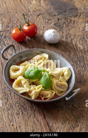 Tortellini auf Holz mit Tomatensauce Stockfoto