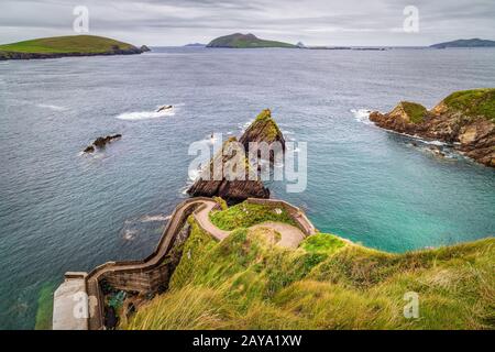 Hohe Klippe an schöner Küste mit Hafen und felsigen Inseln in einer Entfernung Stockfoto