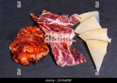 Köstliche spanische Tapas, Vorspeisen wie Chorizo, Schinken und Käse auf schwarzem Schiefer Stockfoto