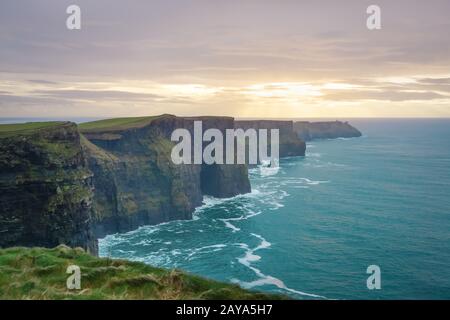 Klippen von Moher auf wilder atlantischer Art mit wunderschönem Sonnenuntergang und türkisfarbenem Wasser Stockfoto