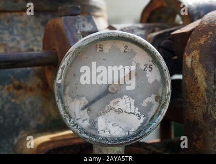 Alte Messuhr mit Nummernspuren auf dem Messrad an einem großen alten rostigen Motor Stockfoto