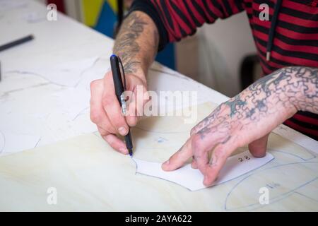 April 2017. Ukraine, Kiew. Die Hände eines Mannes mit einer Filzspitze kennzeichnen die Form einer Schablone auf dem Glas für die Herstellung von gefärbten gla Stockfoto