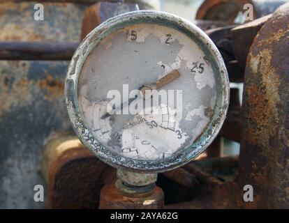 Altes defektes Messgerät an einem alten verrostenen verlassenen Industriemotor Stockfoto