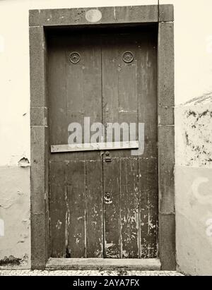 Sepia Vintage-Bild einer geschlossenen Holztür verschlossen und verschlossen mit Nägeln mit Peeling-Lack und Steineinfassung Stockfoto