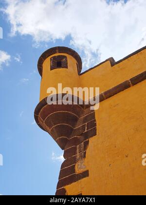 Eine Kuppel an der Ecke des historischen gelben Forts in funchal madeira gegen einen leuchtend blauen Himmel mit weißen Wolken Stockfoto