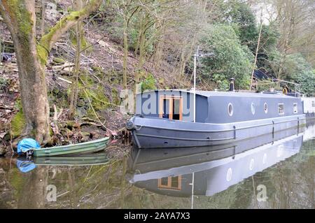 Graues Barge-Hausboot mit grünem Ruderboot auf dem rochdale Kanal in der Nähe der hebdenbrücke Stockfoto