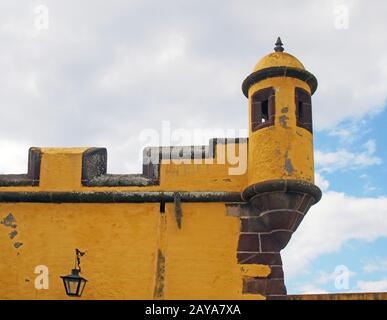 Eine Kuppel an der Ecke des historischen gelben Forts in funchal madeira gegen einen leuchtend blauen Himmel mit weißen Wolken Stockfoto