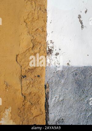 Alte raue bemalte Wand mit abblättertem Betonzerfall mit grauweißen und orangefarbenen Flächen Stockfoto