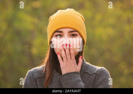 Junge Frau, die ihren Mund mit der Hand bedeckt. Stockfoto