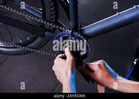 Nahaufnahme der Fahrradmechaniker in der Werkstatt des Menschen mithilfe von Instment, um die Radkurbelbaugruppe, die Fahrradcha, einzustellen und zu reparieren Stockfoto