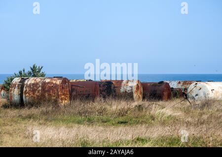 Alte verlassene verwitterte korrodierte Treibstofftanks an der Küste im sonnigen Sommertag Stockfoto