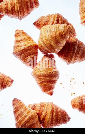 Fallende frische Französische Croissants mit Krümel auf einem hellen Hintergrund. Stockfoto