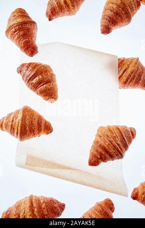 Floating frisch gebackenen Croissant auf einem hellen Hintergrund Pergamentpapier, Mock up. Stockfoto