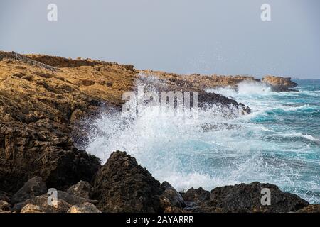 Am Strand von Apostolos Andreas in Karpasia, Zypern, stürzen Meereswellen auf Felsen Stockfoto