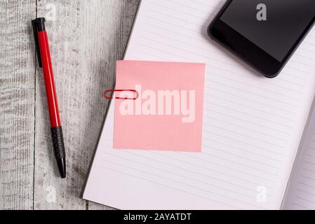 Thick Pages Notizbuch stationär und Gadget auf der Oberseite eines Holztisches. Schreibgeräte mit einem Telefon, das über dem klassischen Look platziert ist Stockfoto