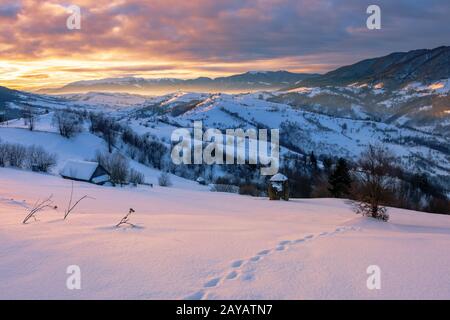 Bergige Landschaft im Winter bei Sonnenaufgang. Schnee bedeckte Hügel und Felder der Karpaten ländlichen Gegend rollt in den Fernen krasna Ridge. glowi Stockfoto