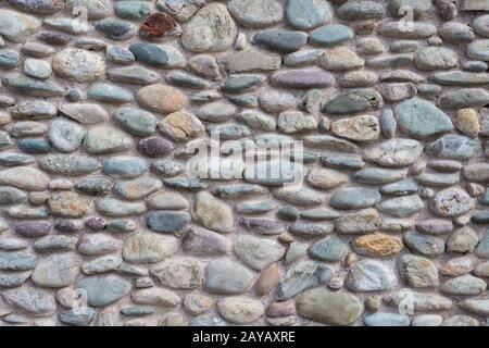 Wand mit bunten zementierten Kieselsteinen Stockfoto