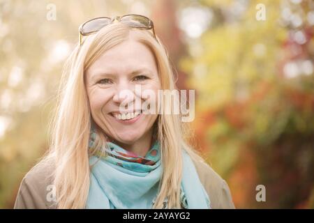 Glücklich und attraktive Frau im herbstlichen Wald lächelnd. Stockfoto