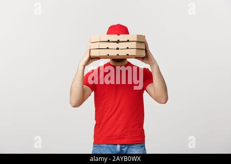 Ein Deliveryman hinter einem großen Stapel von pizzakartons Er trägt, versteckt. Über grauer Hintergrund isoliert. Stockfoto