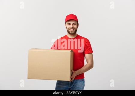 Junge lächelnde Logistik Lieferung Mann in der roten Uniform, die die Box auf weißem Hintergrund Stockfoto