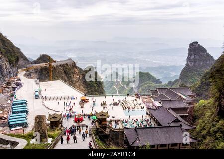 Touristen, die Haven Gate im Tianman Mountain besuchen. Blick auf das Tal und die Einrichtungen darunter Stockfoto