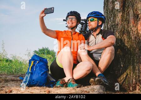 Glückliches Paar mit dem Mountainbike-Rad, das selfie-smartphone im Freien mitnimmt. Ein glückliches Paar, das einen aktiven Lebensstil führt, hielt im an Stockfoto