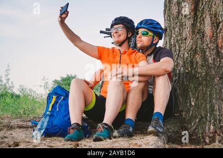 Glückliches Paar mit dem Mountainbike-Rad, das selfie-smartphone im Freien mitnimmt. Ein glückliches Paar, das einen aktiven Lebensstil führt, hielt im an Stockfoto