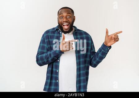 Gerne freuen männlichen Zeigefinger auf leere Kopie Raum, trägt Jeanshemd, hat positive Lächeln. Werbung und Ethnizität Konzept Stockfoto