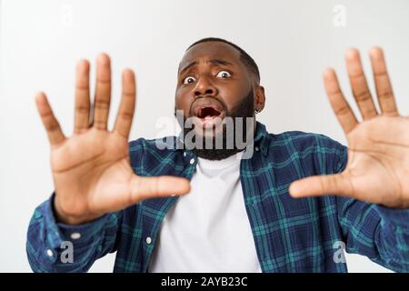 Überrascht junge dunkelhäutige African American man Student an der Kamera starrte mit schockierten Blick. Stockfoto