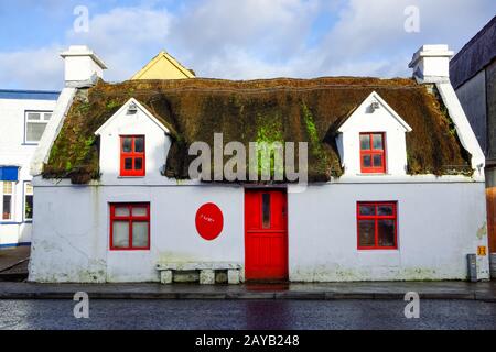 Altes, ruiniertes und verlassenes Reethaus mit roten Fenstern und Tür Stockfoto