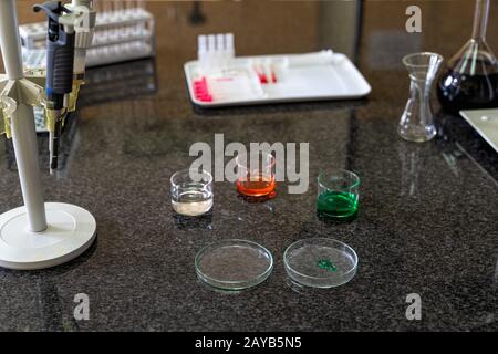 Pipette und bunte Lösungen für chemische Flüssigkeiten in Kolben auf Laborarbeitsplatten Stockfoto