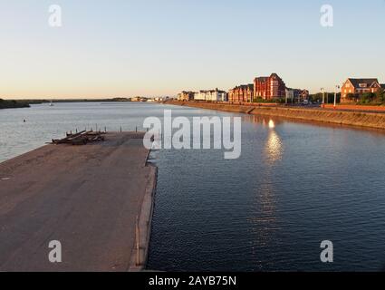 Blick über den See in southport bei Sonnenuntergang mit einem Steg vor den Gebäuden am Wasser Stockfoto