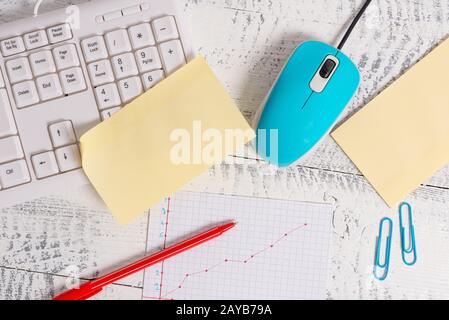 Schreibgeräte und Computerwerkzeuge sowie Grafikbild auf Holzkulisse. Stationär, Maus, Notizpapier in der Nähe der Tastatur Stockfoto