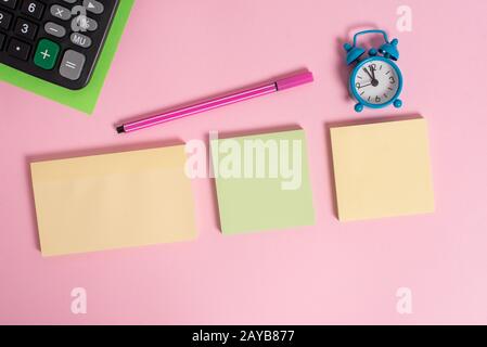 Drei mehrfarbige leere Notizblöcke Wecker Wakeup Marker-Taschenrechner farbener Hintergrund leerer Text wichtige Ereignisse Home o Stockfoto