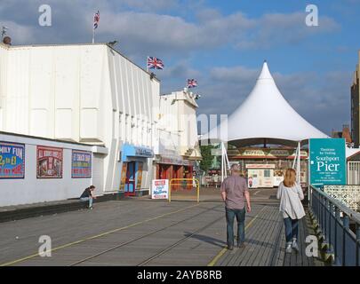 Menschen, die in die Einfahrt zum southport Pier in merseyside gehen, mit einem Karussell und einer Spielhalle Stockfoto