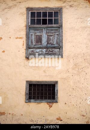 Zwei alte Holzfenster mit alten verblichenen grünen Farbbalken aus Metall blenden und Platten auf einer alten verputzten Schälbetonierung Stockfoto