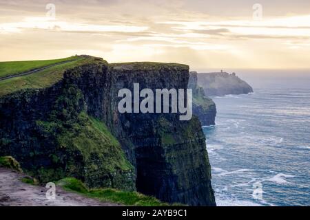 Die Klippen von Moher, die in den wilden Atlantik mit Ruinen des Turms am Rande der Klippe Stockfoto