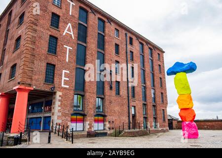 Außenansicht der Kunstgalerie Tate Liverpool im Albert Dock Area in Liverpool, Merseyside, mit einer Skulptur von Ugo Rondinone benannt Stockfoto