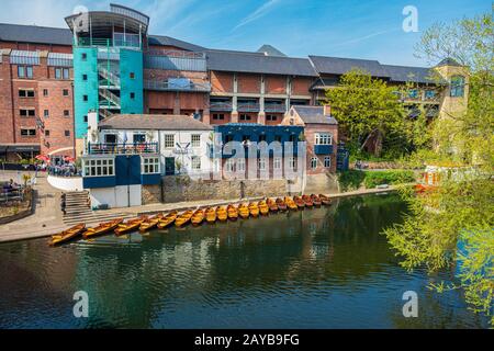 Eine Reihe von vermoorten Ruderbooten am Ufer des Flusses tragen in der Nähe eines Bootsklubs in Durham, Großbritannien an einem schönen Frühlings-Nachmittag Stockfoto