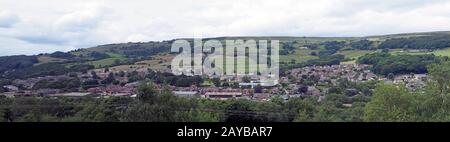 Ein langer Panoramablick auf die Stadt Mytholmroyd von oben mit Gebäuden und Straßen der Stadt, die im Tal mit su sichtbar sind Stockfoto