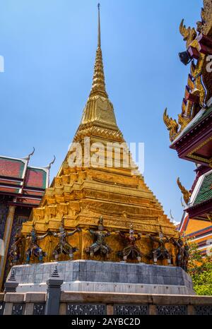 Riesige Statuen an der Basis der Goldene Pagode in Wat Pra Keo im Grand Palace Stockfoto