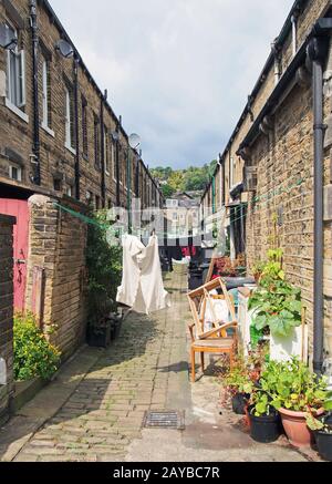 Eine Hintergasse zwischen Straßen mit Reihen traditioneller Steinhäuser in hebden Brücke West yorkshire mit Waschtrocknung auf Linien Stockfoto