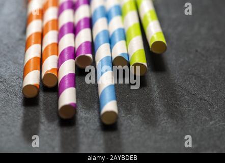 Mehrfarbige Getränkestrauten auf dunklem Steingrund. Leuchtende Farben kontrastieren bei natürlichem Licht. Stockfoto