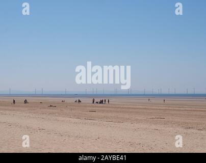 Blick auf einen großen flachen, sandbedeckten Sommerstrand in formby merseyside mit unerkennbaren Menschen in der Mitteldistanz und Wind Stockfoto