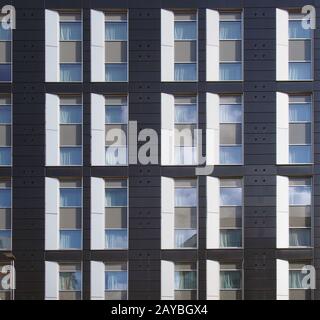 Fassade eines großen, schwarz-weiß-modernen Geschäftshauses mit sich wiederholenden Fenstern und geometrischen Paneelen Stockfoto