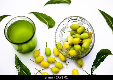 Entgiftung oder Entgiftung von Niemfrüchten in einem Glas, das auf Weiß isoliert ist, zusammen mit einigen Niemfrüchten oder Nimbodi oder Nimbudi in einer Glasschale.Horizontaler Schuss Stockfoto