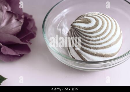 Ein Marshmallow in einem Glas Vase neben einer Rose. Stockfoto
