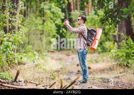 Mann Wanderer, der Foto-Smartphone in Wald nimmt. Attraktiver Reisender, Der Mit Dem Mobiltelefon Fotos Macht. Reisender Wanderer mit Backpa Stockfoto