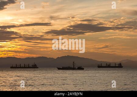 Boote, die während eines Sonnenuntergangs auf den Hafen von Caldera warten. Haupthafen im Pazifik von Costa Rica. Stockfoto